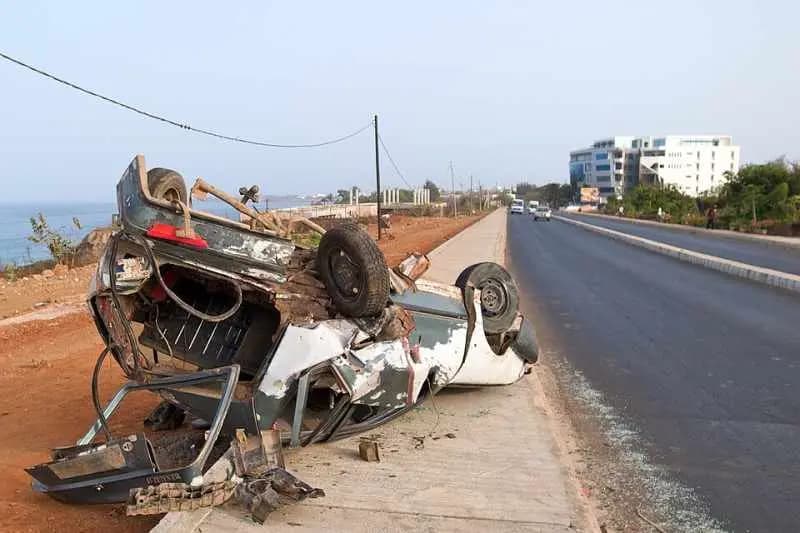 Épave d'une voiture retournée au bord d'une route de la côte à Dakar après un accident de la circulation