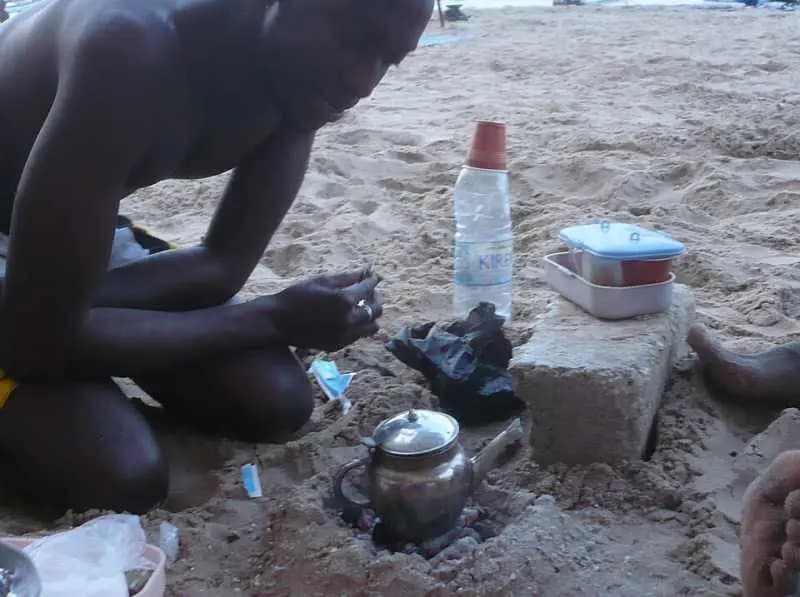 Préparation de l'ataya, le thé sénégalais, sur un petit réchaud à charbon posé dans le sable