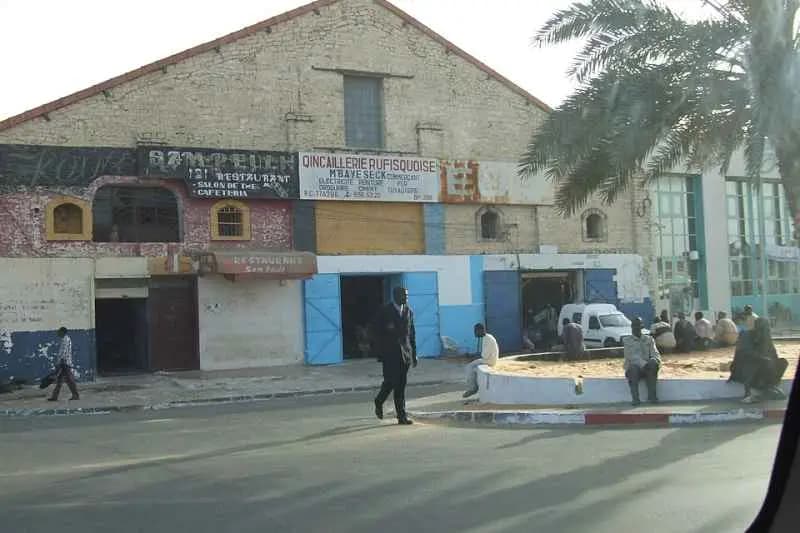 Façades de locaux commerciaux, dont une quincaillerie, le long d'une rue de Rufisque près de Dakar