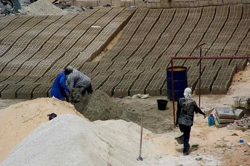 Maçons au travail sur un chantier de briques et de sable à Dakar