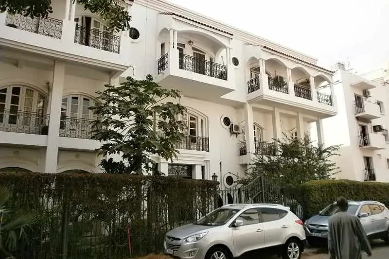 Immeuble d'habitation blanc à balcons et arcades dans un quartier résidentiel de Dakar
