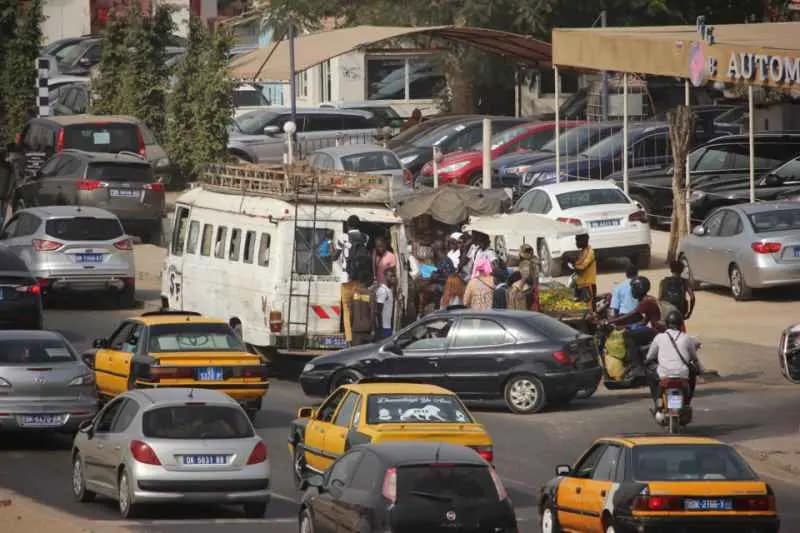 Embouteillage dans une rue de Dakar : voitures particulières, taxis jaunes et minibus pris dans la circulation