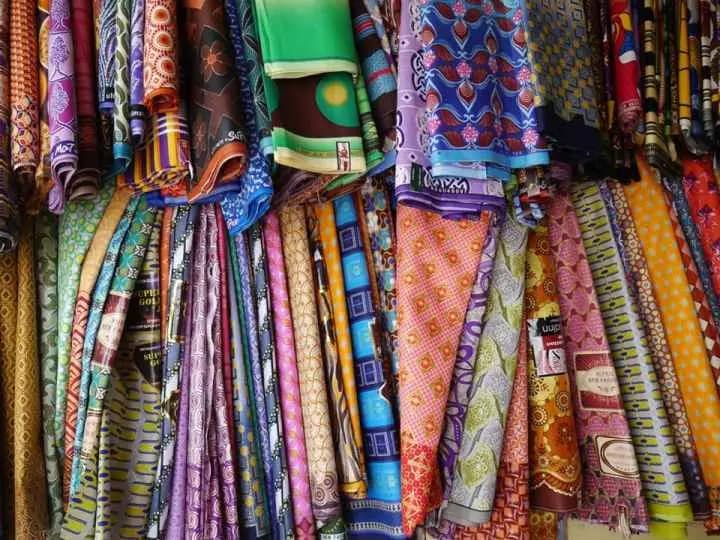Pagnes wax aux motifs colorés empilés dans une boutique de tissus au Sénégal