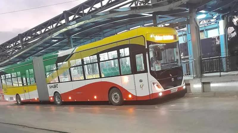 Bus BRT articulé jaune, rouge et vert arrêté à une station de Dakar