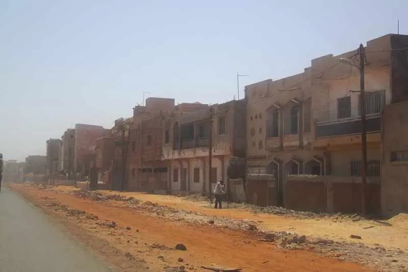 Rangée de maisons le long d'une rue en terre à la sortie de Dakar