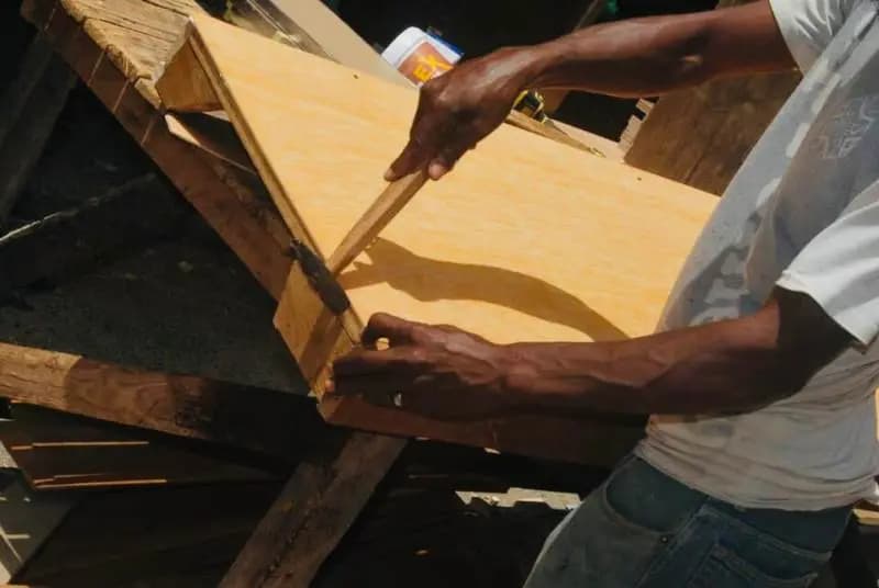Menuisier assemblant une planche de bois dans son atelier de la Médina à Dakar