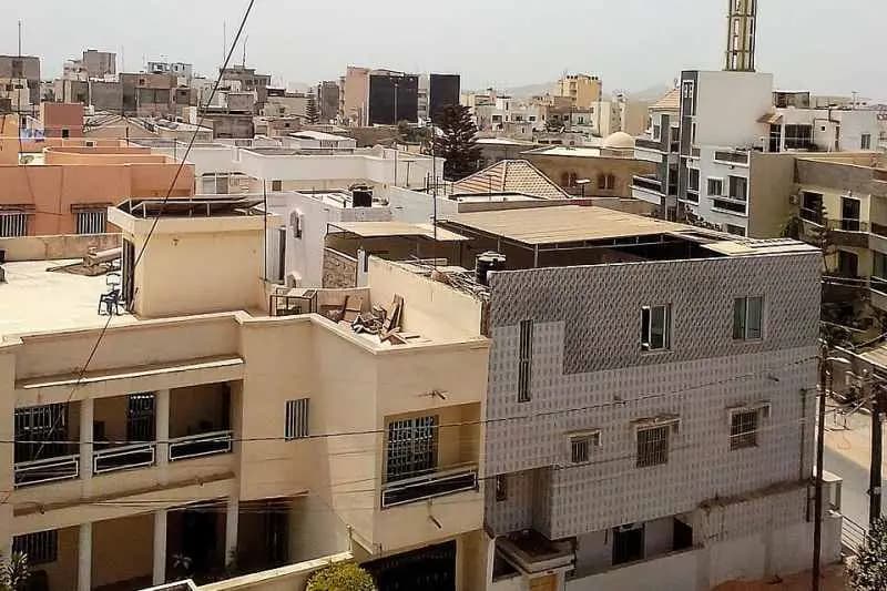 Maisons à étages et toits-terrasses d'un quartier résidentiel de Dakar, avec des immeubles en arrière-plan