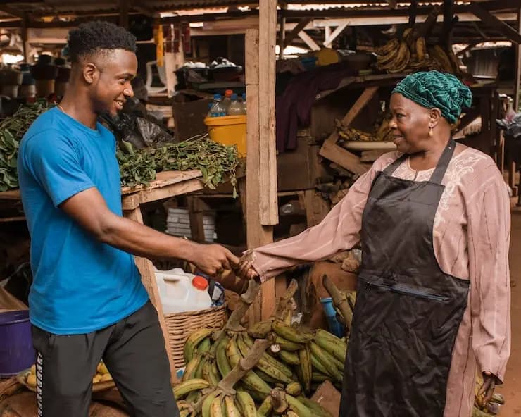 Client réglant son achat auprès d'une commerçante sur un étal de marché