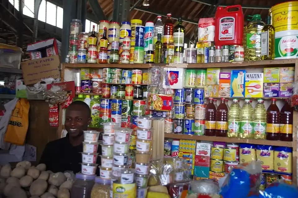 Étal d'épicerie du marché Kermel à Dakar : huiles, conserves et produits emballés alignés sur des étagères
