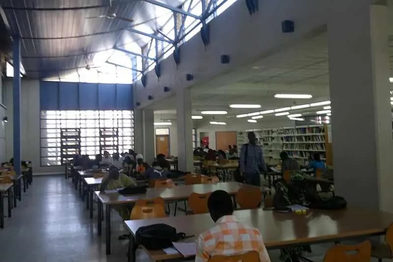 Étudiants installés aux longues tables de la salle de lecture de la bibliothèque universitaire de l'UCAD, à Dakar
