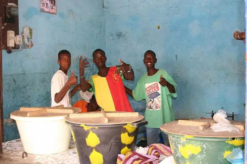 Trois jeunes devant leurs seaux de lait caillé dans une petite boutique de Saint-Louis