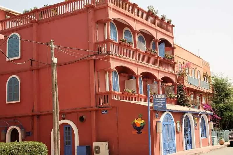 Hôtel de style colonial à la façade rouge et aux balcons de bois à Saint-Louis du Sénégal
