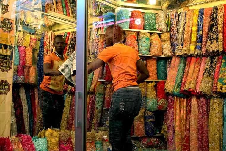 Employés d'une boutique de tissus devant des étagères de pagnes aux motifs colorés