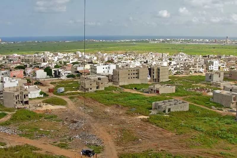Parcelles et constructions inachevées dans un quartier en extension de la banlieue de Dakar, avec l'aéroport au fond