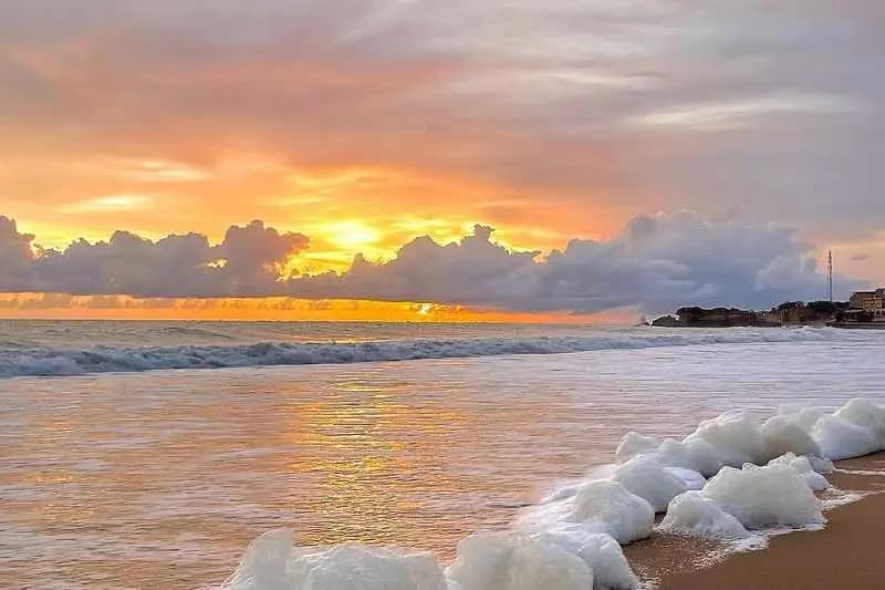 Coucher de soleil sur la plage de Popenguine, dans la réserve naturelle, avec l'écume des vagues sur le sable