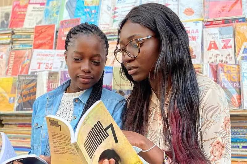 Deux étudiantes consultant ensemble un livre devant un étal de livres